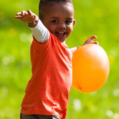 19475877 - outdoor portrait of a cute young  little black boy playing with a balloon - african people